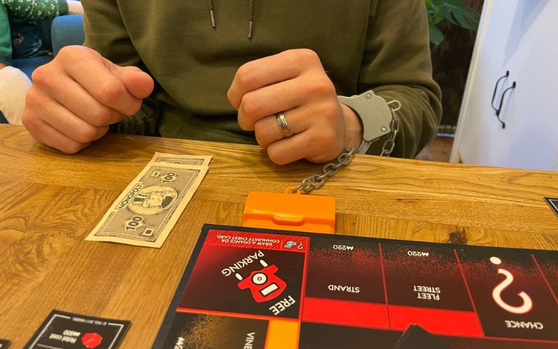 handcuffed hand while playing monopoly cheaters edition