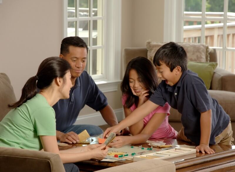 Family playing Monopoly with kids