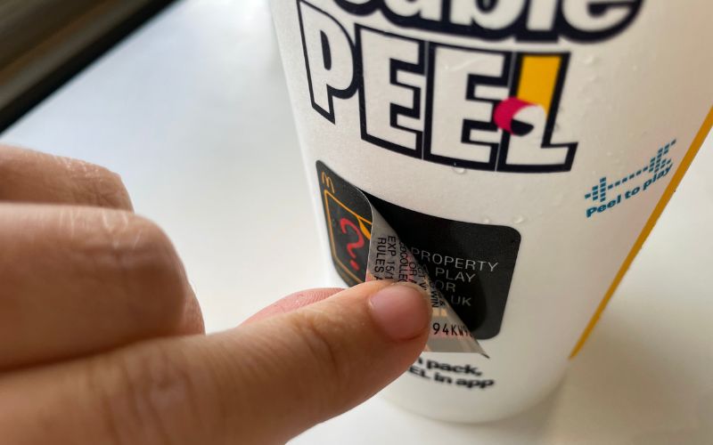peeling monopoly sticker on McDonalds cup