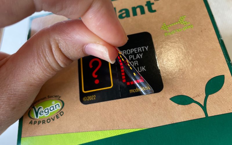 peeling monopoly sticker on McDonalds food item