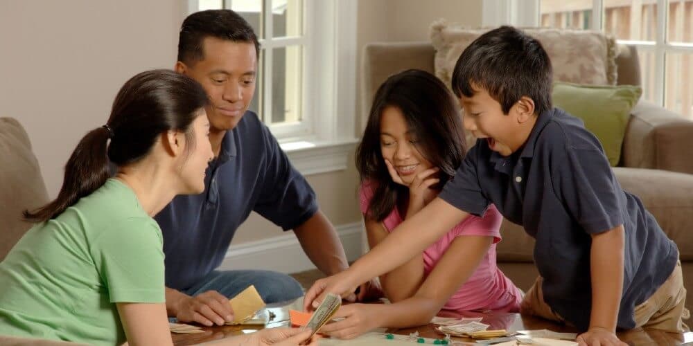 family playing Monopoly with kids in teams